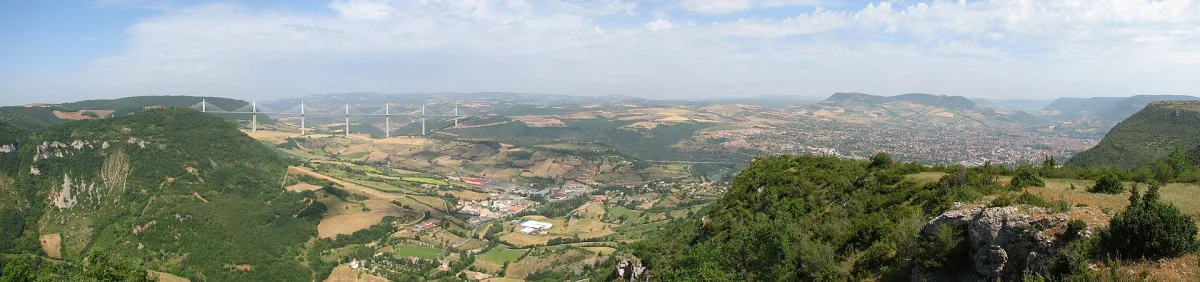 Le viaduc de Millau vu depuis un belvédère, ses pylônes émergeant de la brume matinale au-dessus de la vallée du Tarn