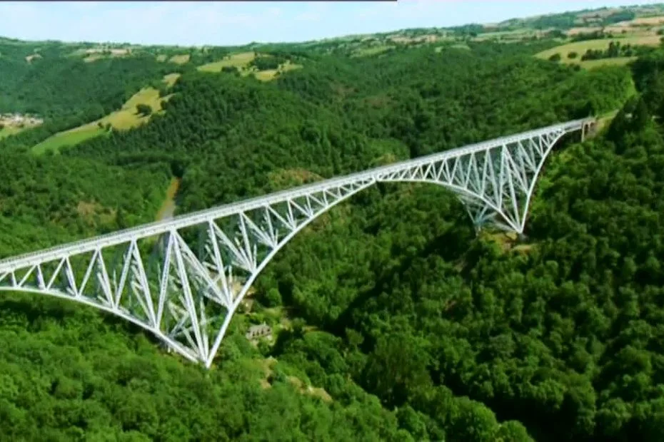 Vue du viaduc métallique du Viaur enjambant les gorges boisées, structure en arc et pylônes de fer visibles au-dessus de la rivière